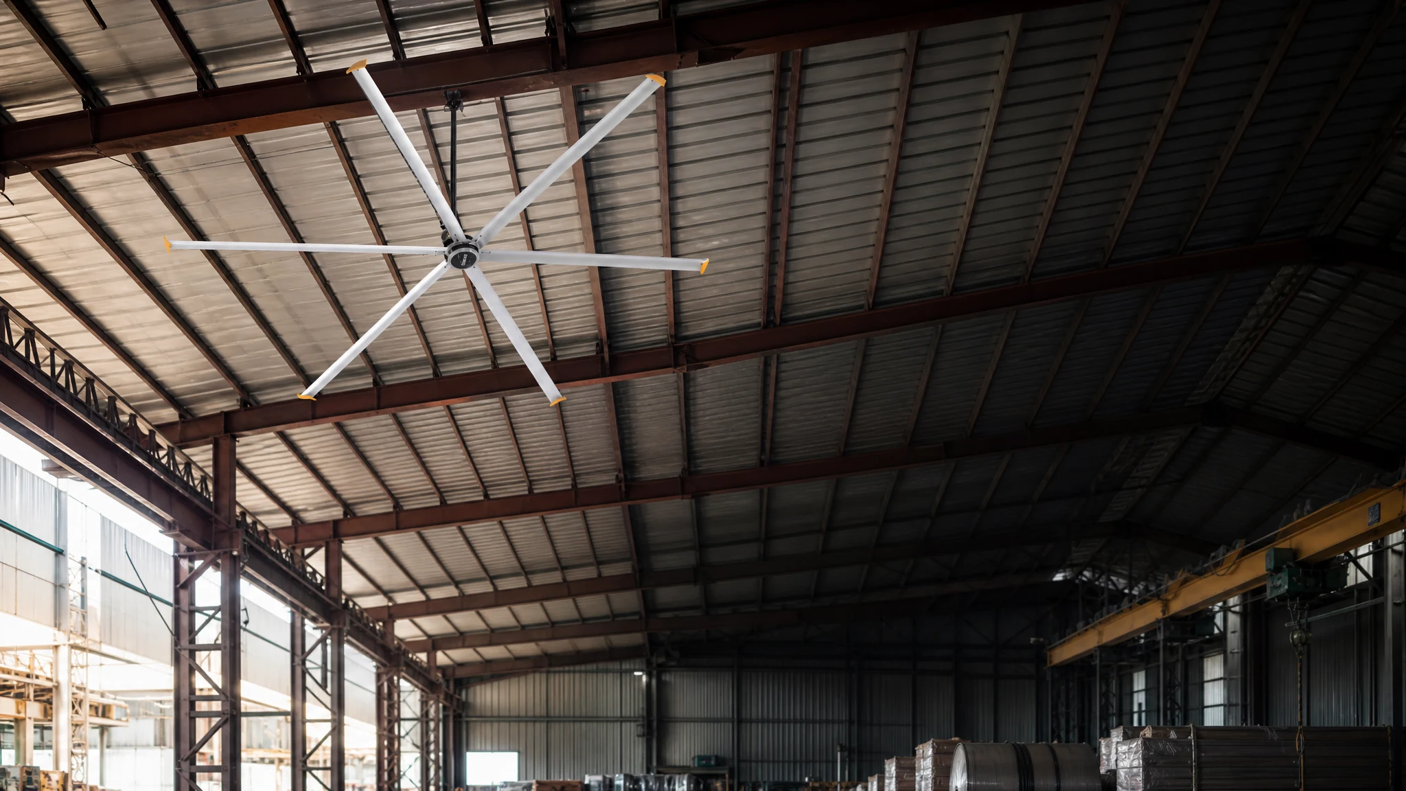 Six-blade HVLS ceiling fan installed below a steel warehouse roof